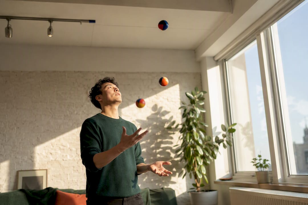 Person juggling stress balls in home workspace
